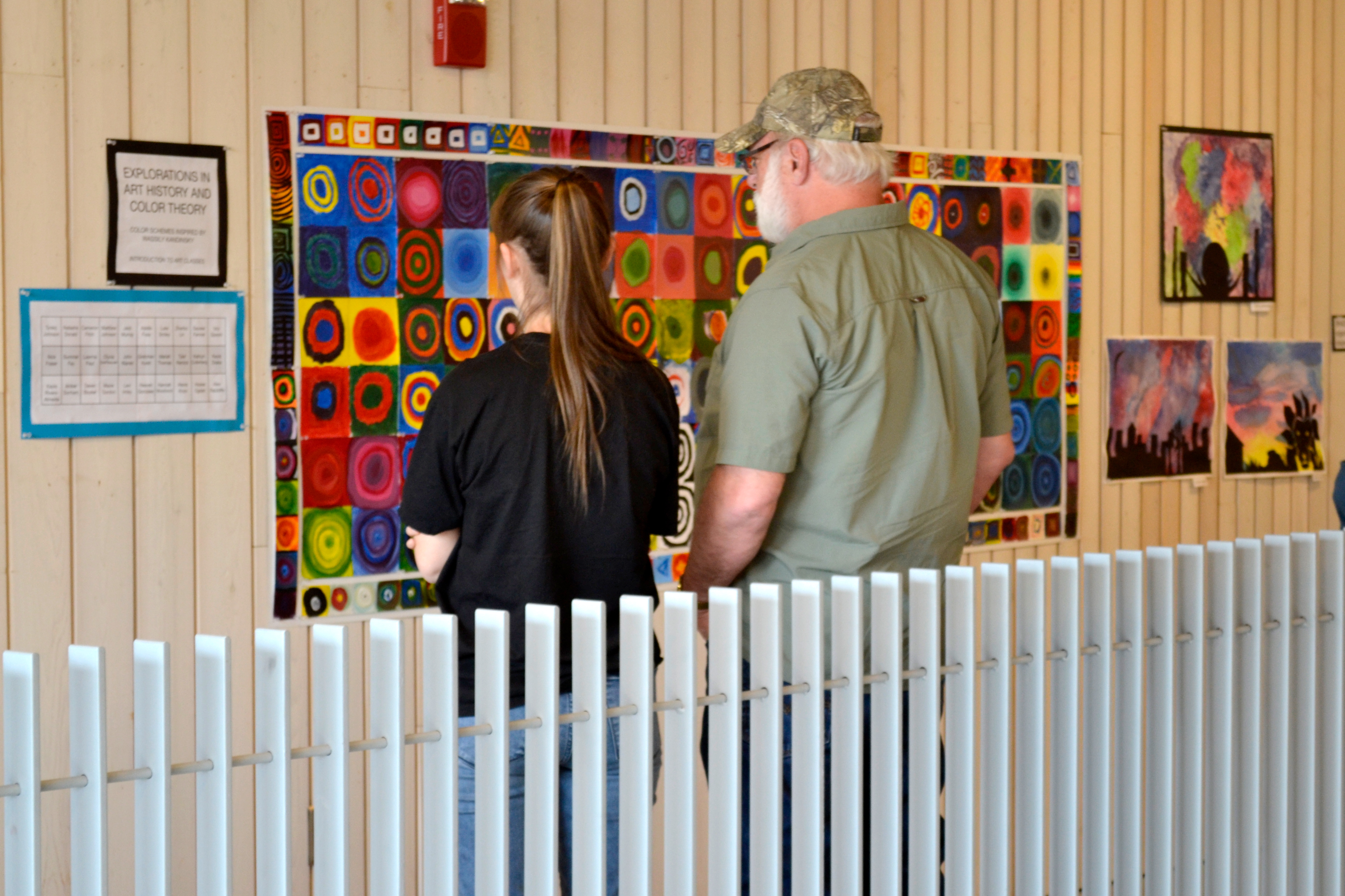 Two people observe a colorful mural together.