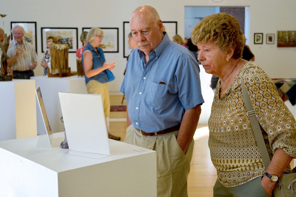 Two visistors observe artwork together.