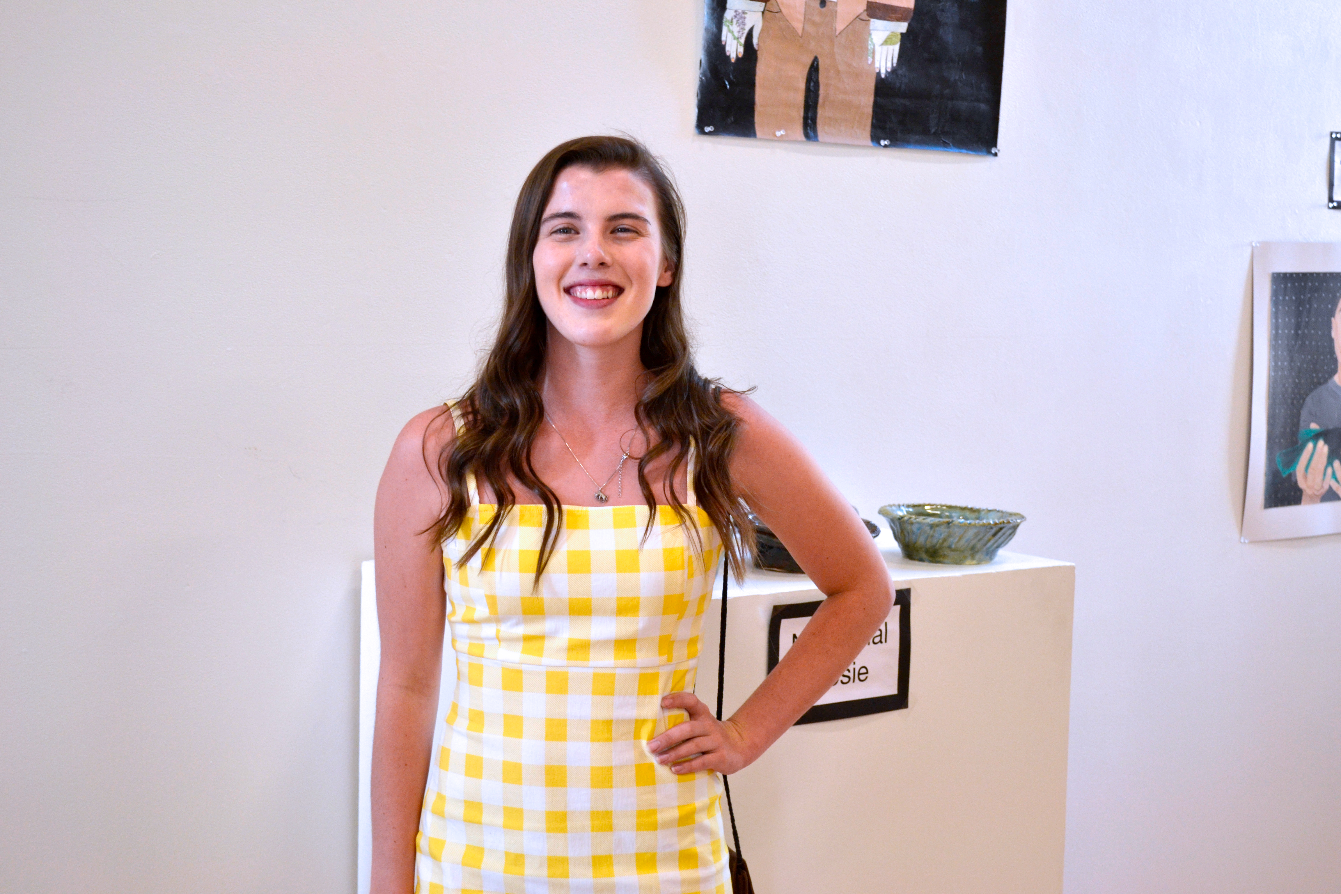 A student artist smiles proudly at the camera.