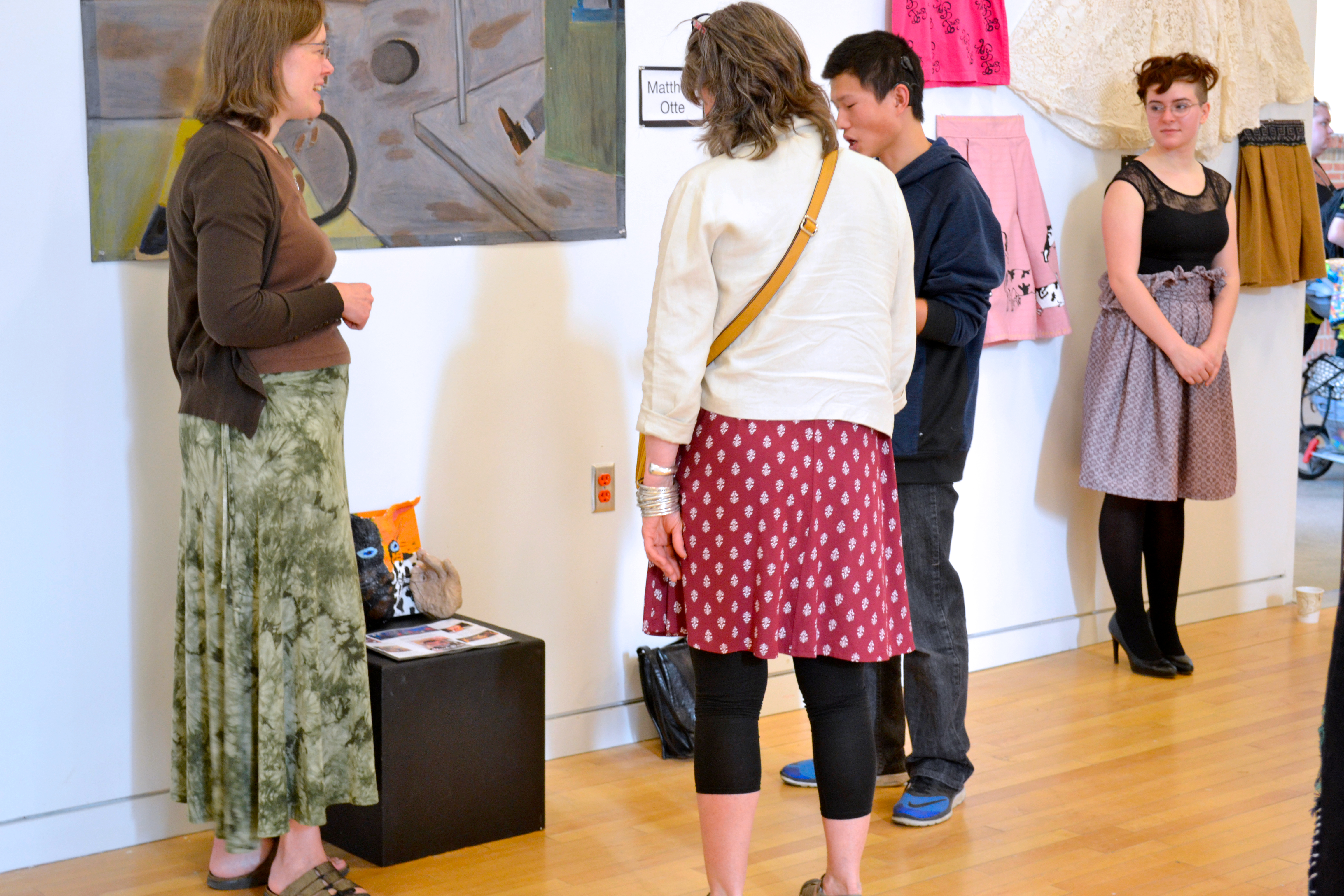 An artist discusses his work with people attending the opening.