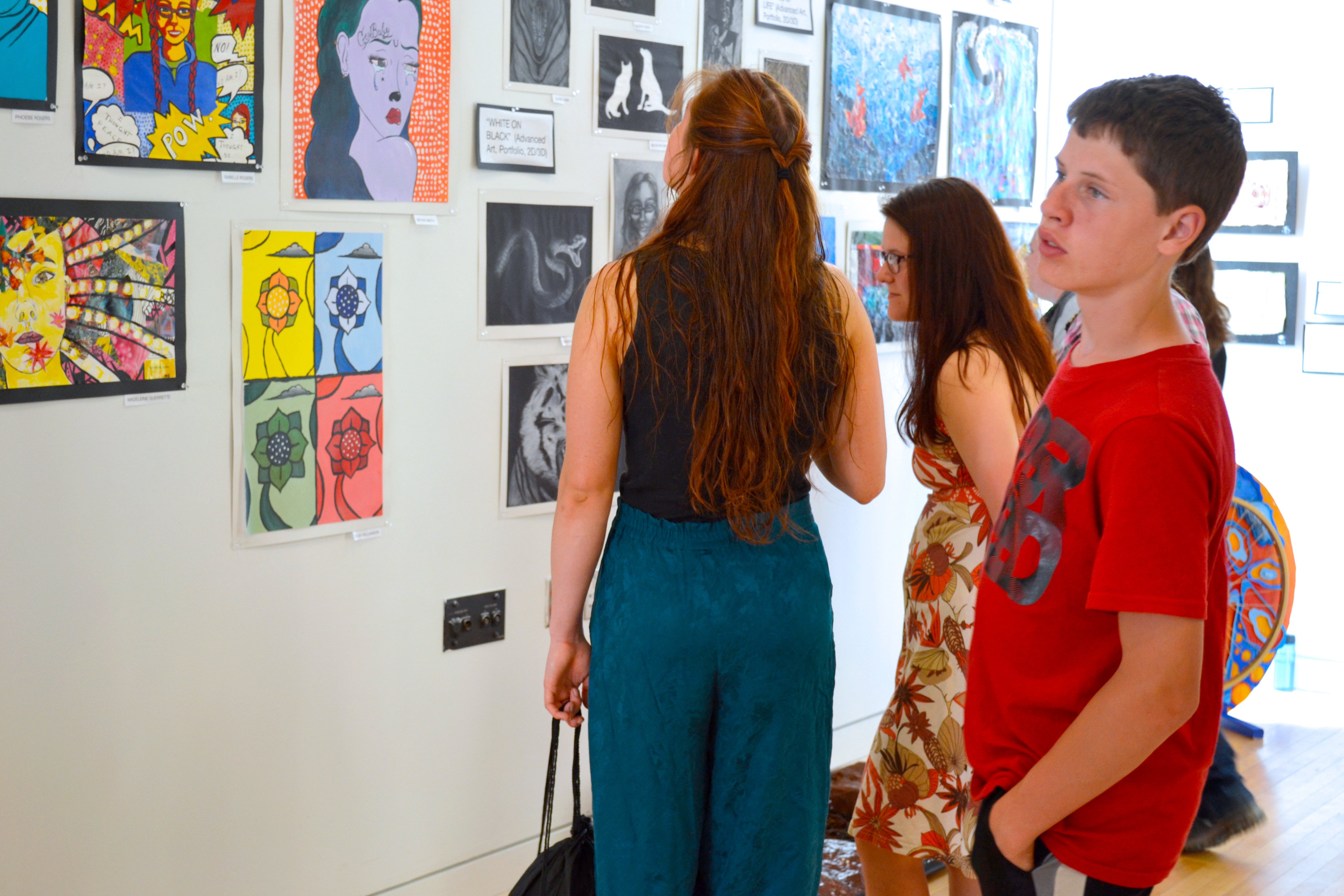 A boy gazes across a gallery wall at a section of artwork.