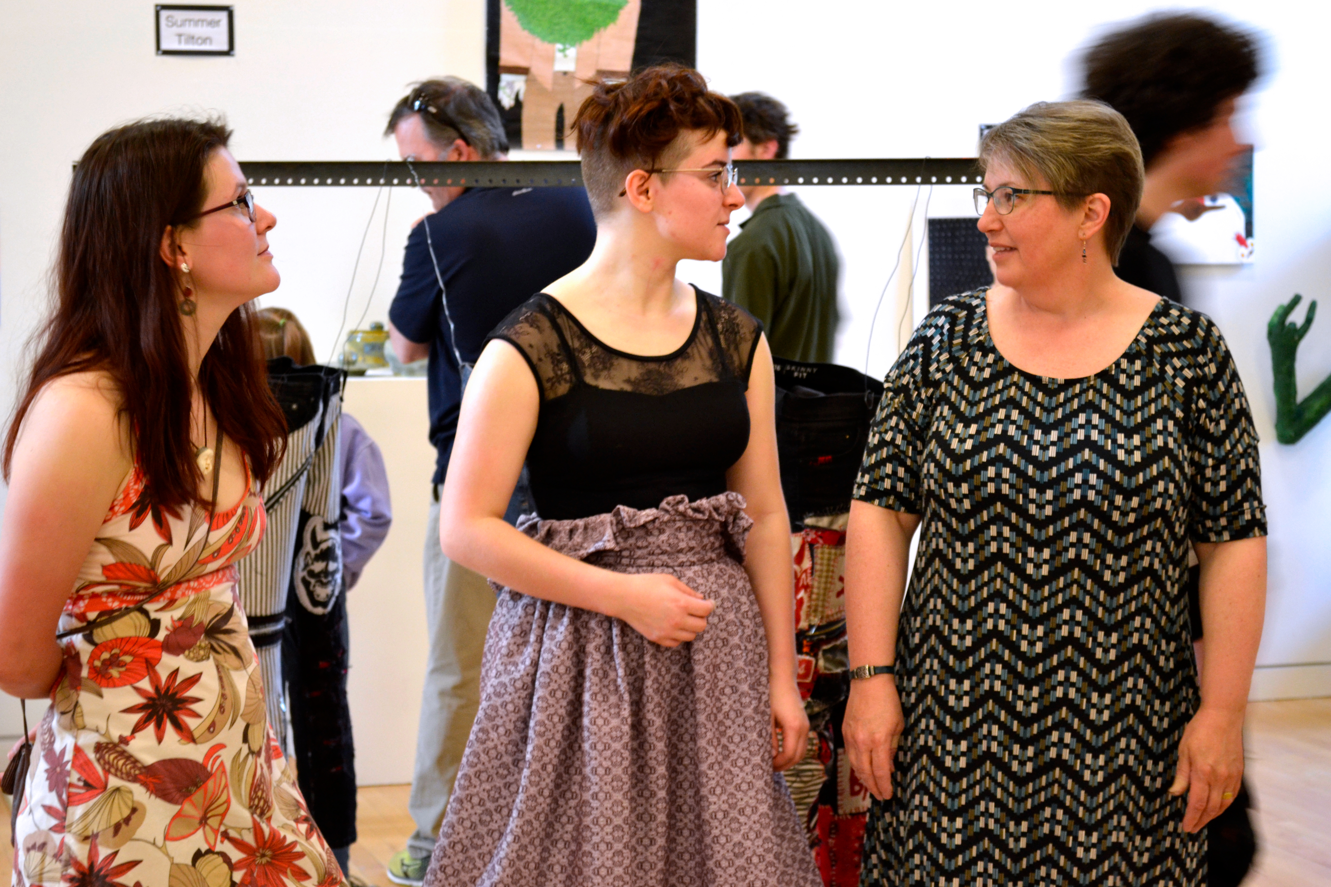 A group of three talk with each other about the artwork.