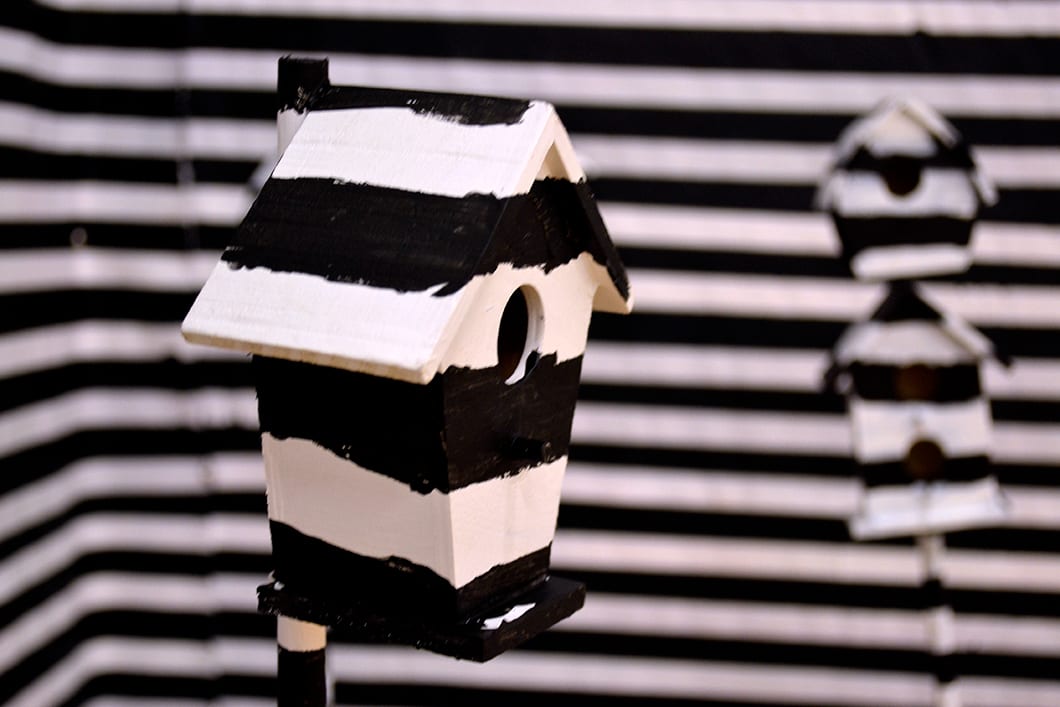 Striped birdhouses camouflage into a similar background.