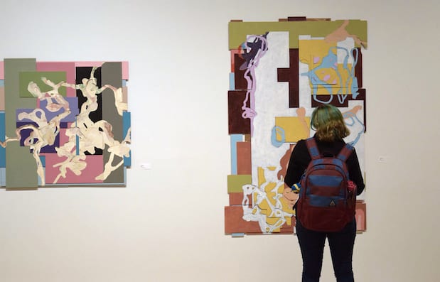 Student looking at Tom Jessen's painting in the gallery.