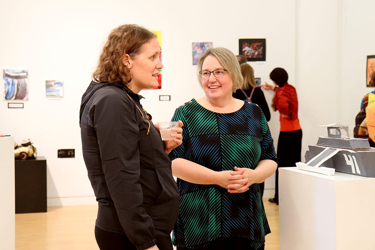 Patrons discuss artwork at the MBHS opening reception.
